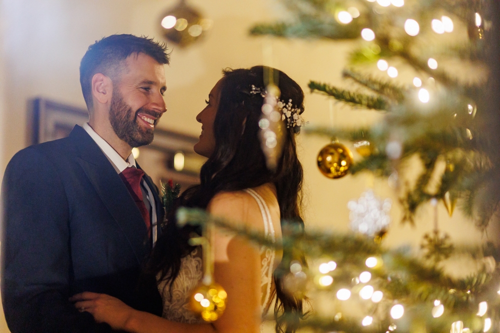 bride and groom next to a christmas tree 