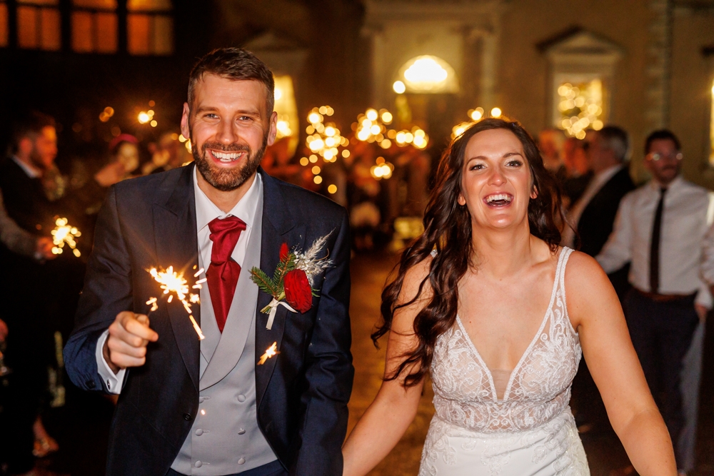 bride and groom walking out with sparklers around them 