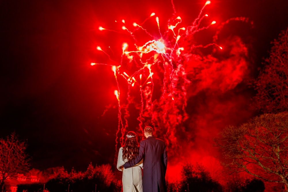 bride and groom with fireworks behind them 