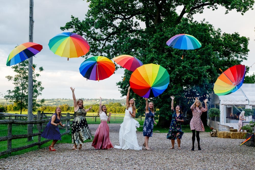 wedding guests throwing colourful umbrellas in the air