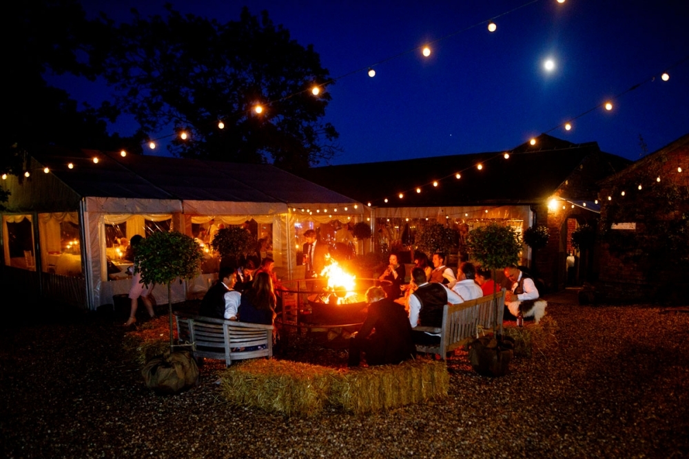wedding guests drinking outside by the fire